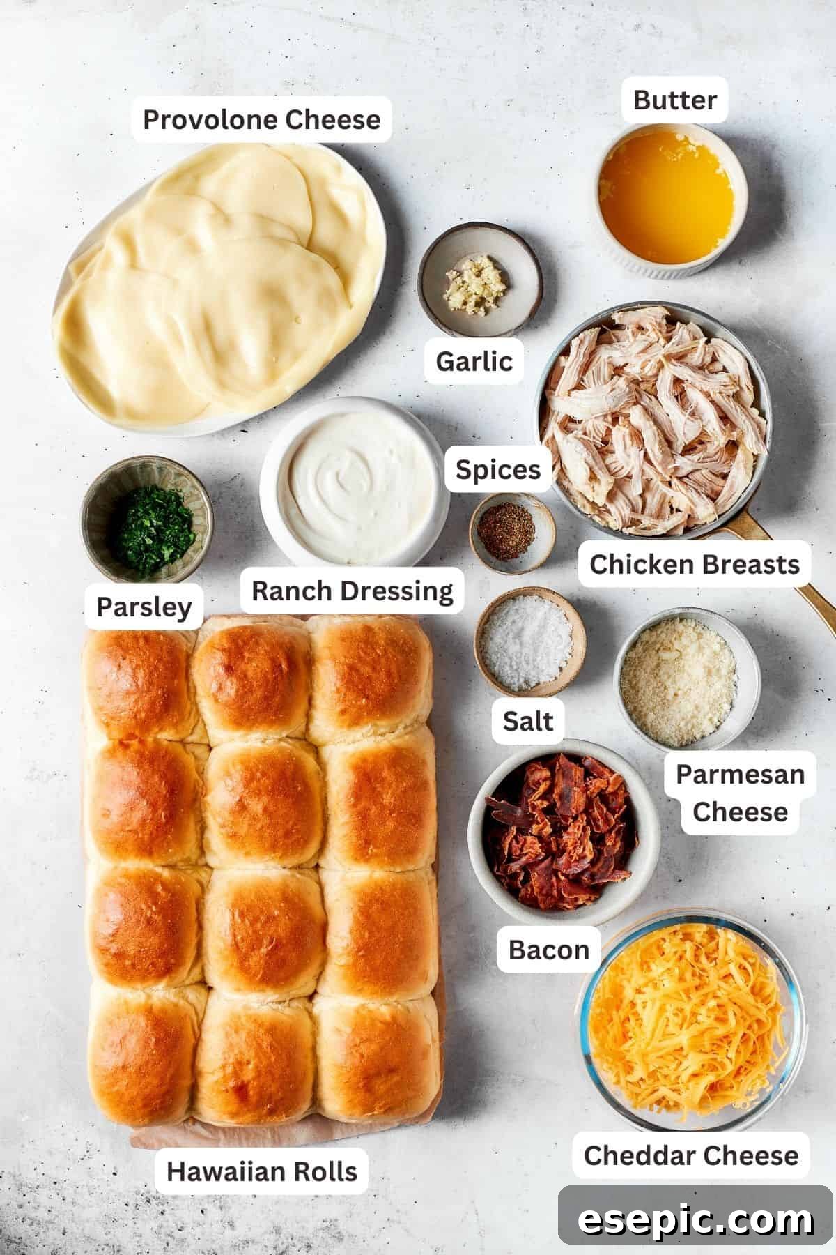 The ingredients for chicken bacon ranch sliders laid out: sweet rolls, provolone cheese, cheddar cheese, parmesan cheese, shredded chicken, salt, bacon, ranch dressing, parsley, minced garlic.