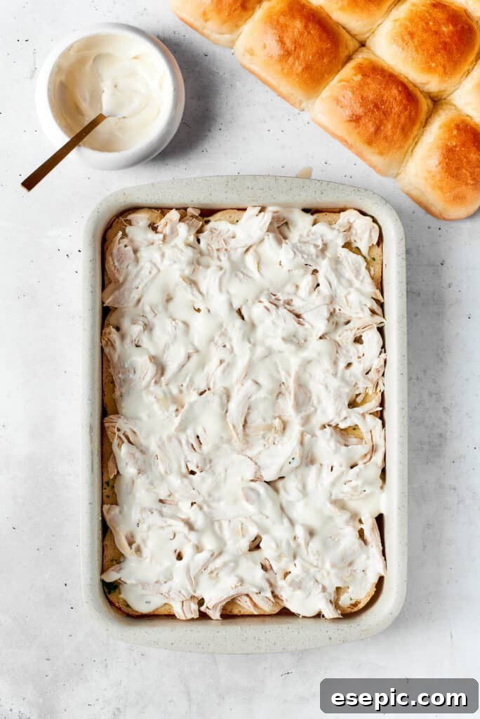 Ranch dressing and crumbled bacon topping the shredded chicken layer on the sliders.