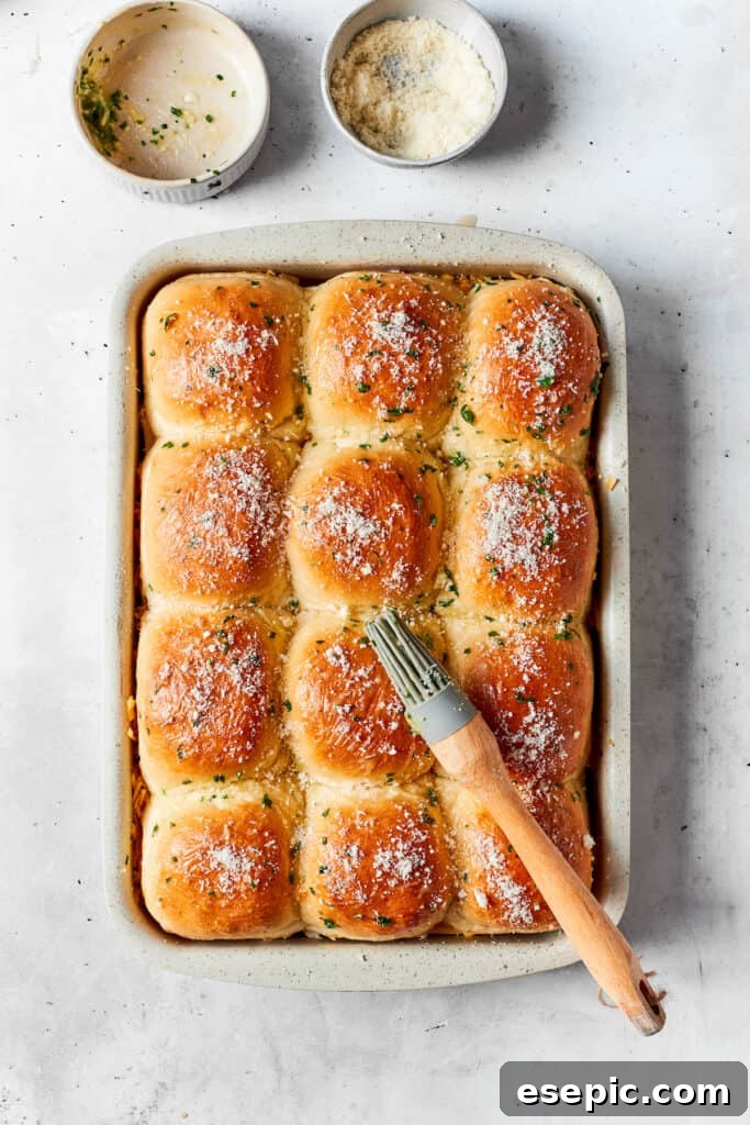 The tops of the Hawaiian rolls being brushed with the remaining melted garlic butter mixture.