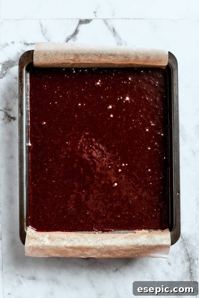 Evenly spreading brownie batter in the pan. Brownie batter is spread into a baking pan.