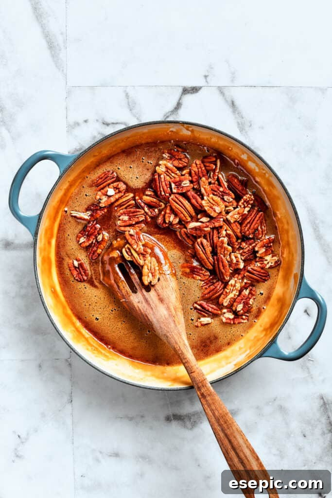 Gently folding pecans into the caramel mixture. Pecans are mixed in.
