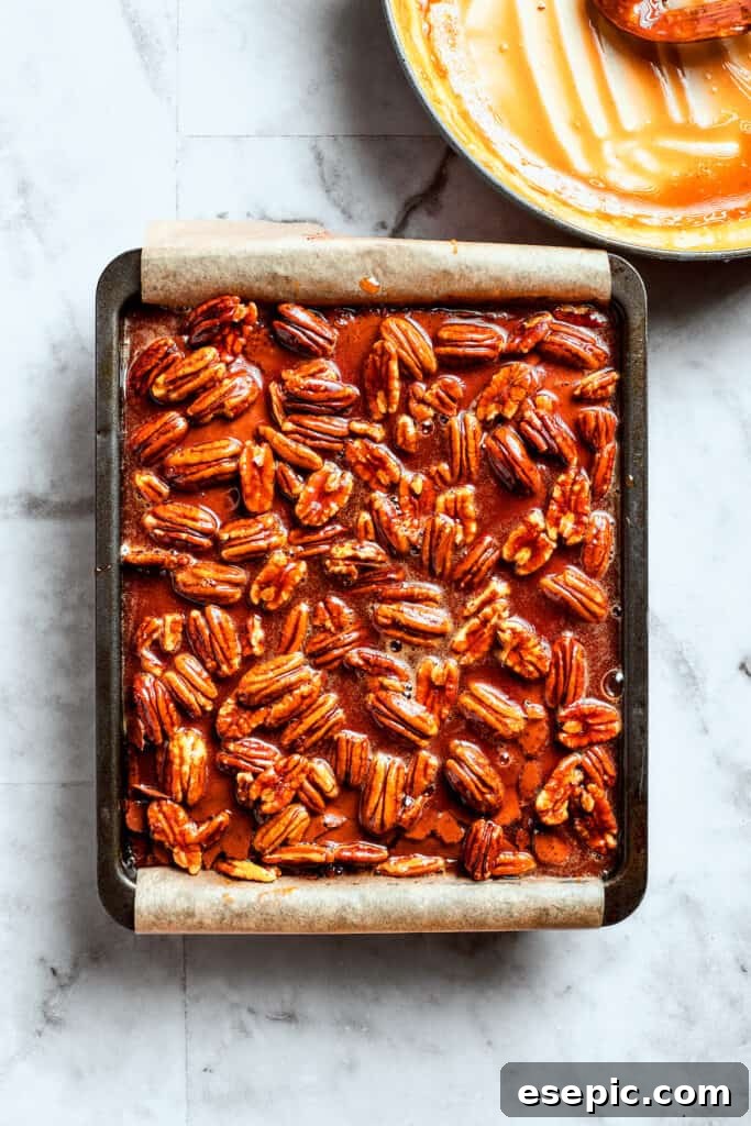 Pouring the rich pecan pie filling over warm brownies. The pecan pie filling is added to the top of the brownies.