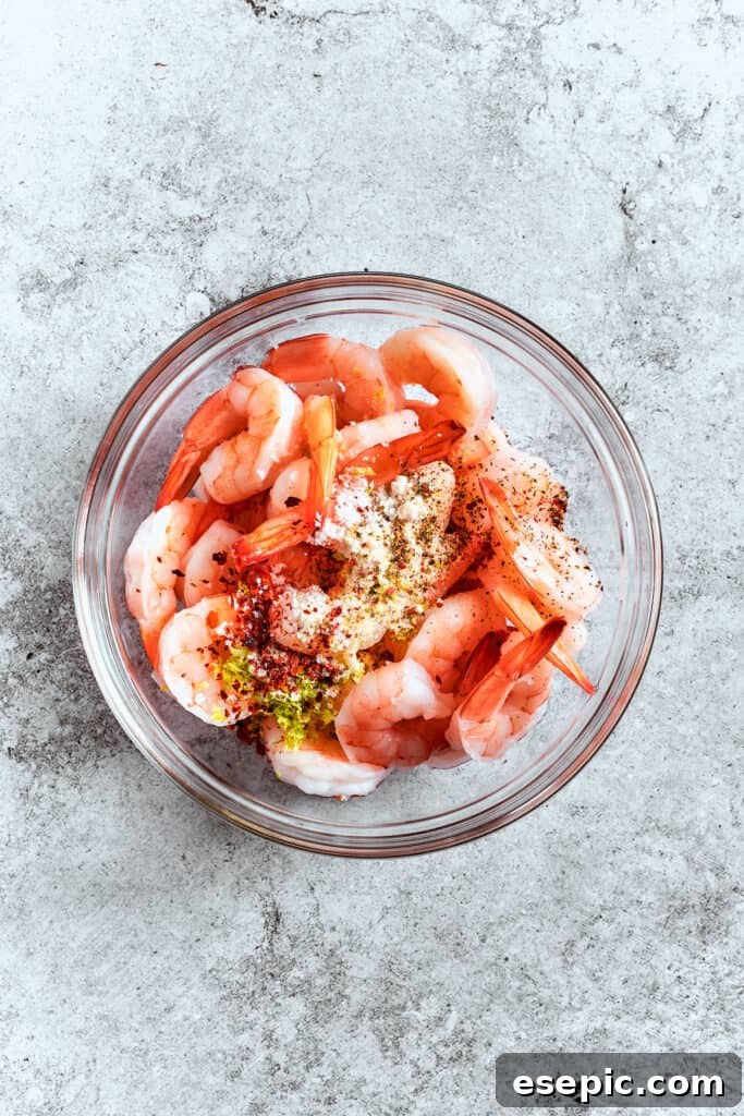 Seasonings are added to shrimp in a bowl.