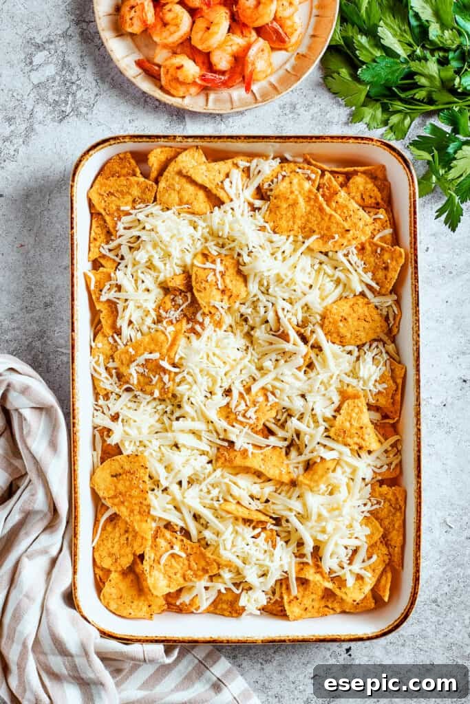 Shredded cheese is added to the nachos.