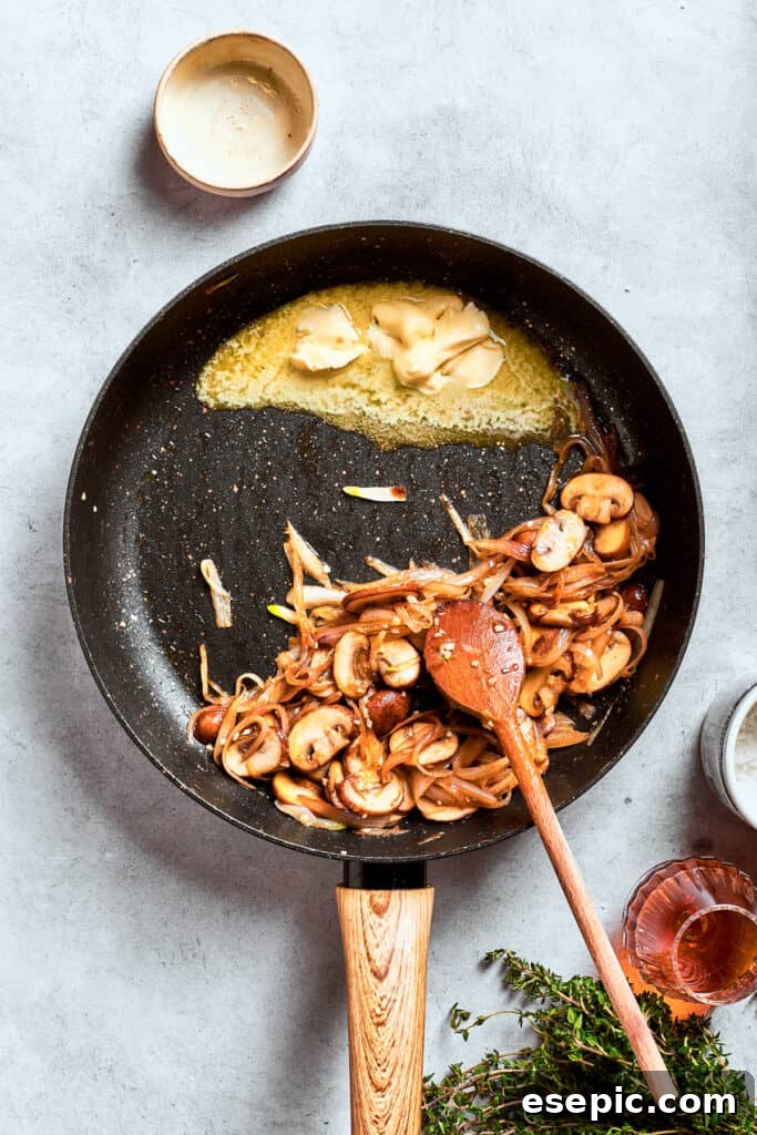 The cooked mushrooms are pushed to one side of the pan, making space for other ingredients.