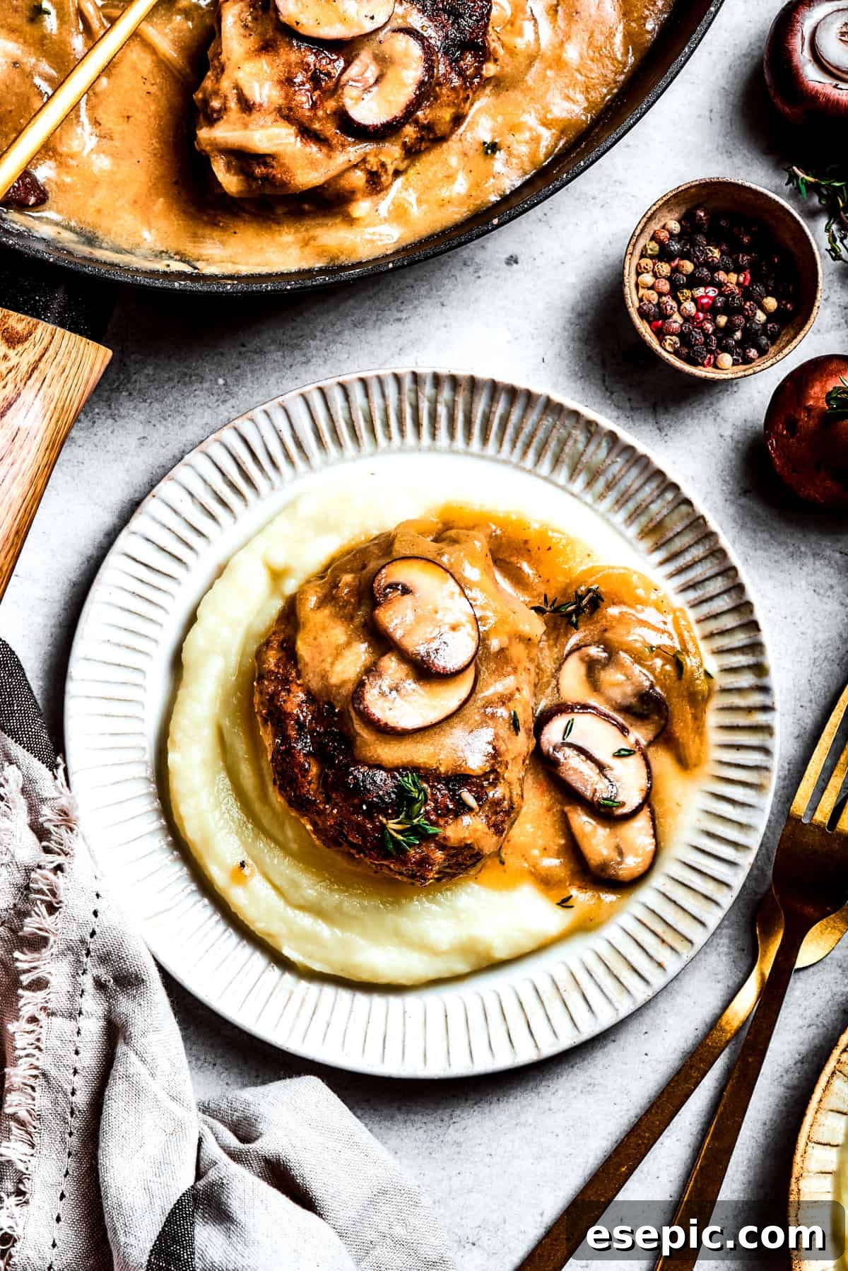 A generous serving of chopped steak is artfully placed on top of creamy mashed potatoes, ready to be enjoyed.