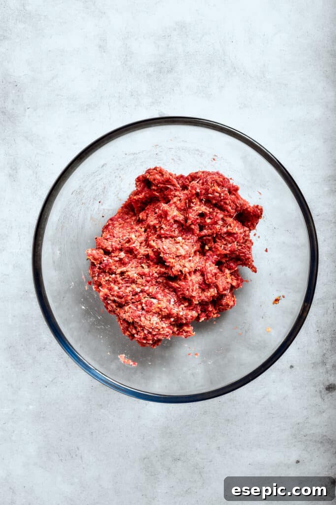 The egg and breadcrumbs are meticulously mixed into the ground beef, ensuring an even distribution for the patties.