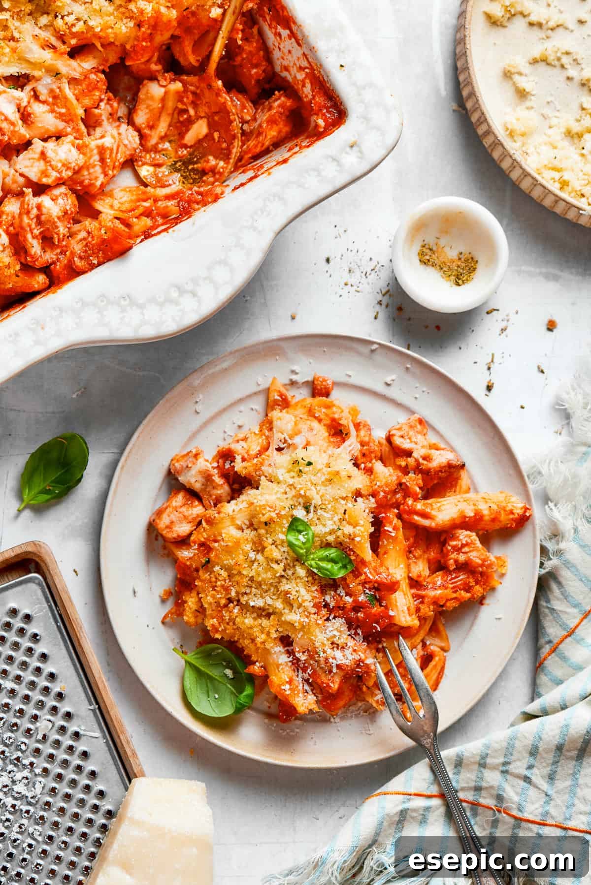 A perfectly portioned plate of Chicken Parmesan Casserole, showcasing the layers of pasta, chicken, sauce, and melted cheese, with a fork ready to dig in.