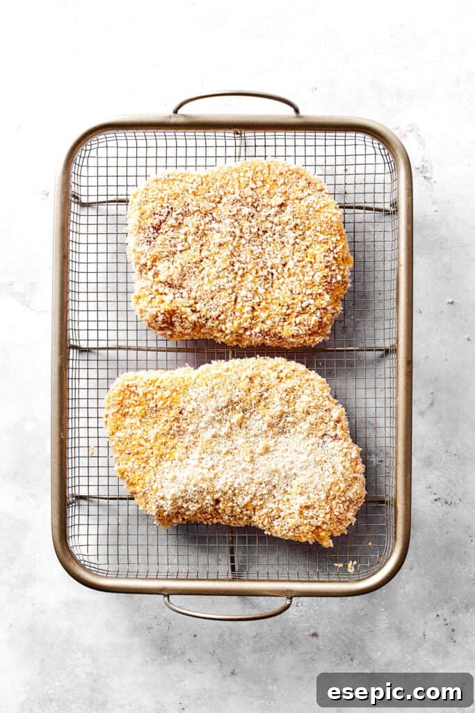 Arranging breaded pork on a rack before frying. Freshly breaded pork cutlets are neatly arranged on a wire rack, ready for frying.