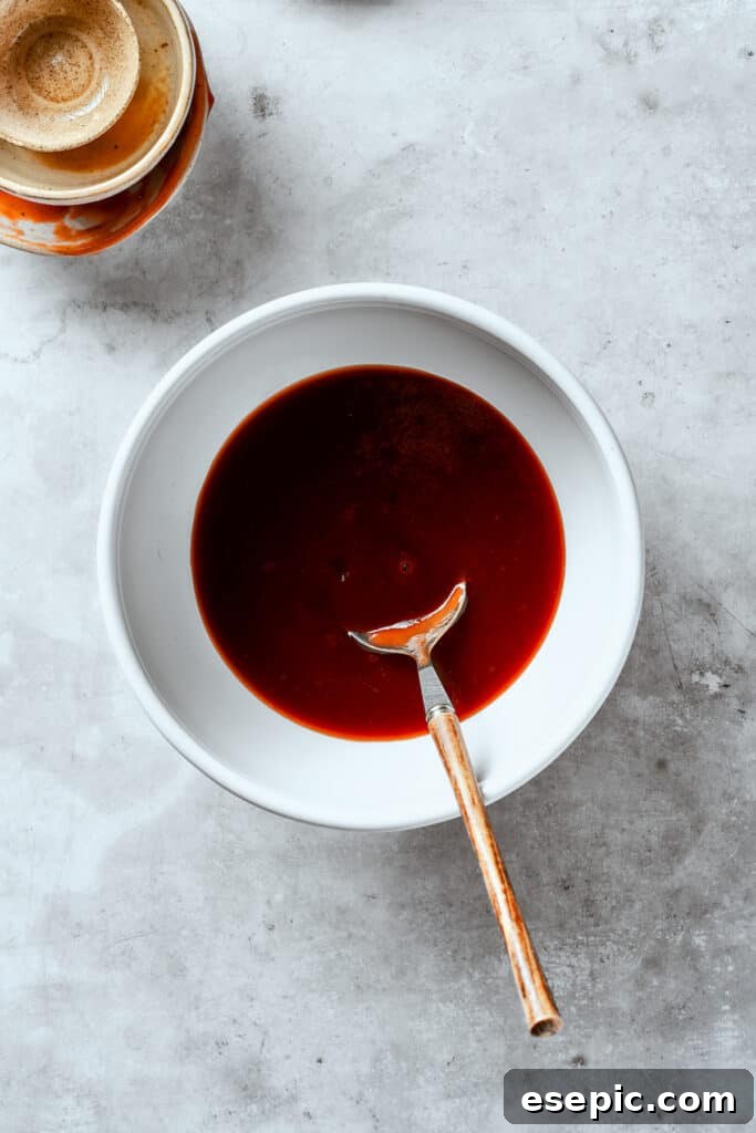 The first step: preparing the flavorful Tonkatsu sauce. Tonkatsu sauce is skillfully stirred in a bowl, showing its thick, rich texture.
