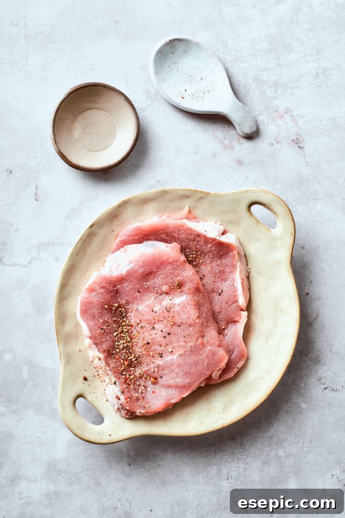 Seasoning the pork chops for maximum flavor. Pork cutlets are meticulously seasoned with salt and pepper, preparing them for breading.