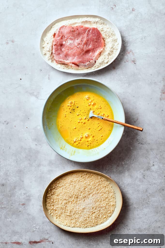 Setting up the crucial breading station. A perfectly organized breading station, featuring three shallow bowls: one with seasoned flour, one with beaten eggs, and one with crispy Panko breadcrumbs.