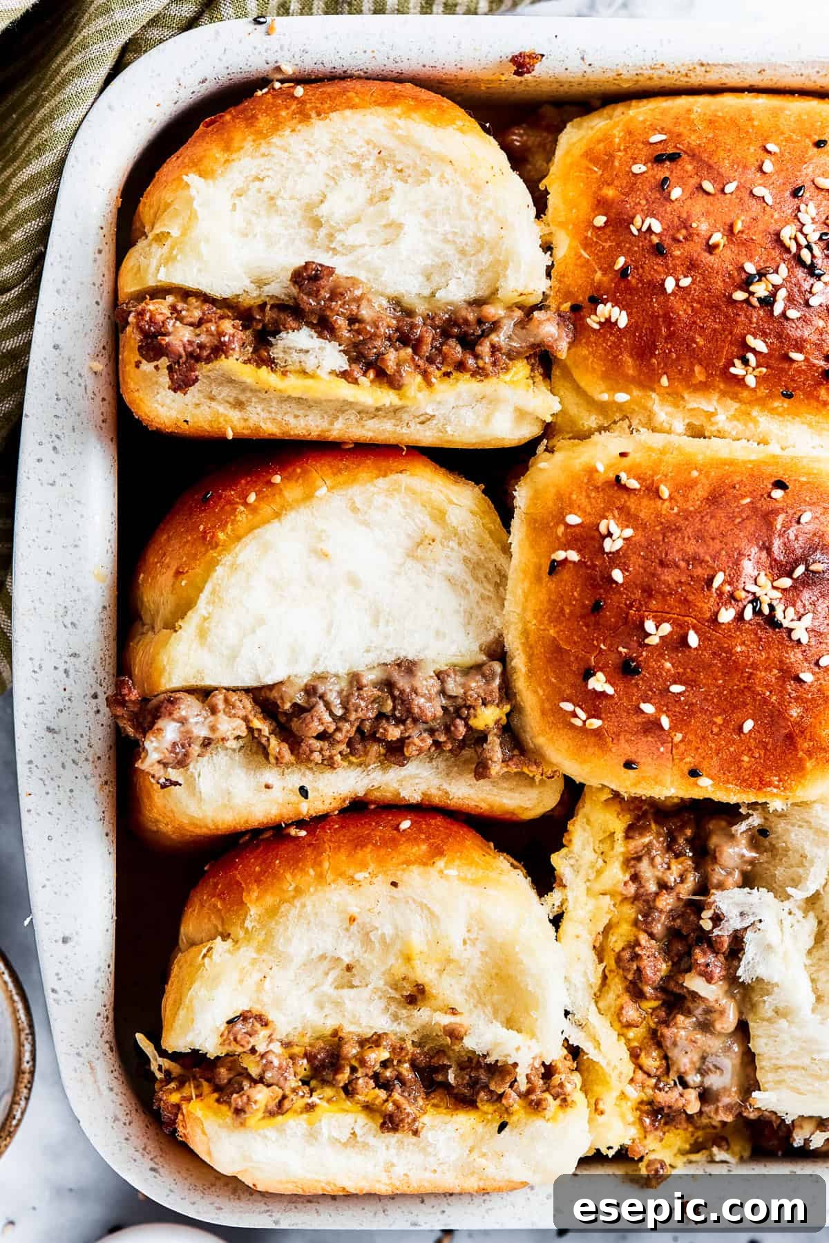 Three perfectly baked cheeseburger sliders, showing their golden rolls and savory filling, ready to be enjoyed.