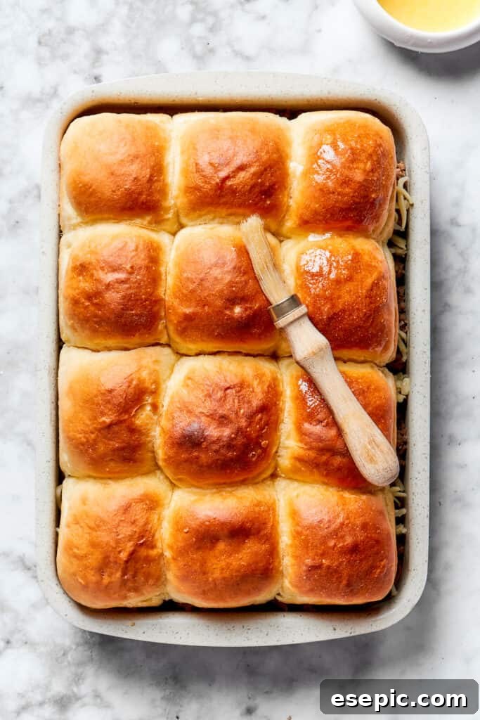 Melted butter infused with garlic powder is generously brushed over the tops of the dinner rolls, adding flavor and promoting a golden-brown crust.