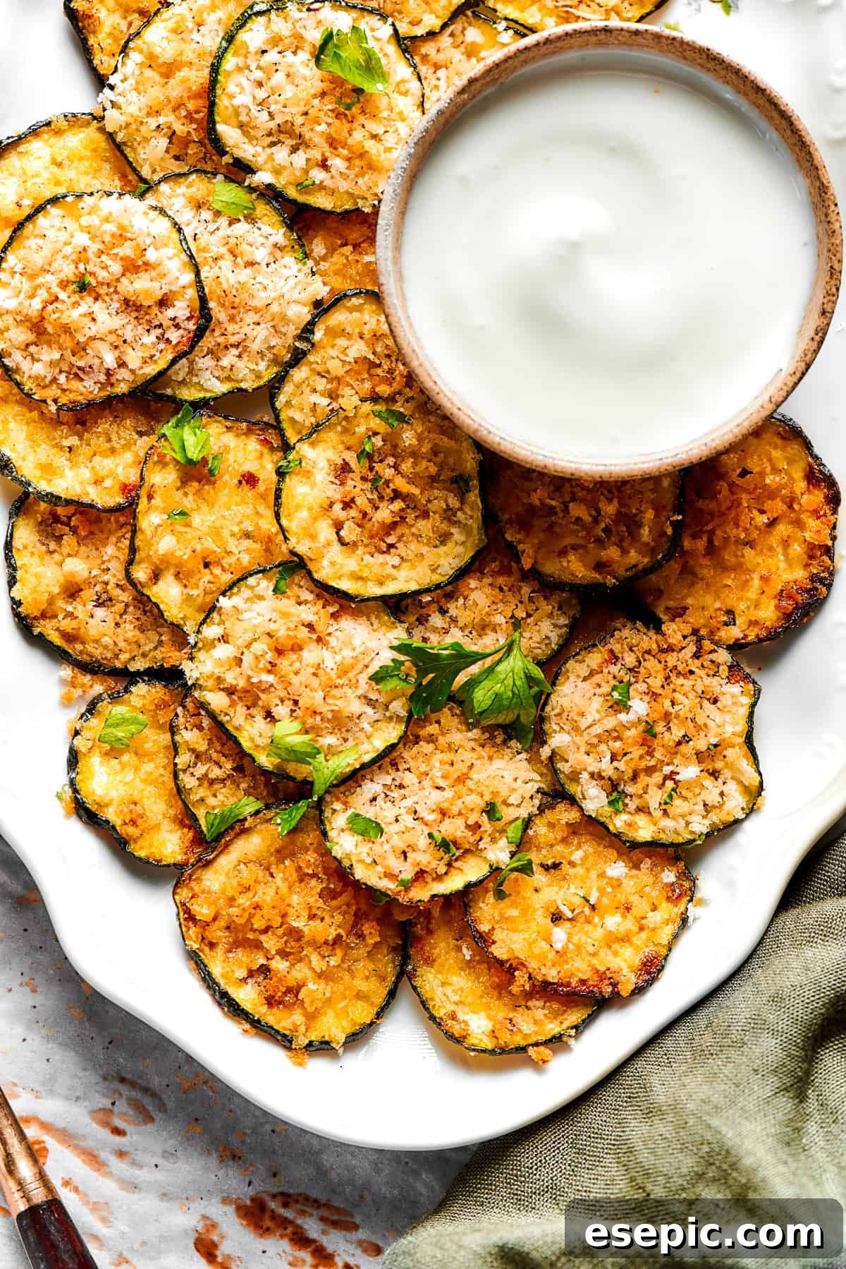 A vibrant platter of crispy zucchini chips, generously garnished with fresh herbs, ready to be enjoyed.