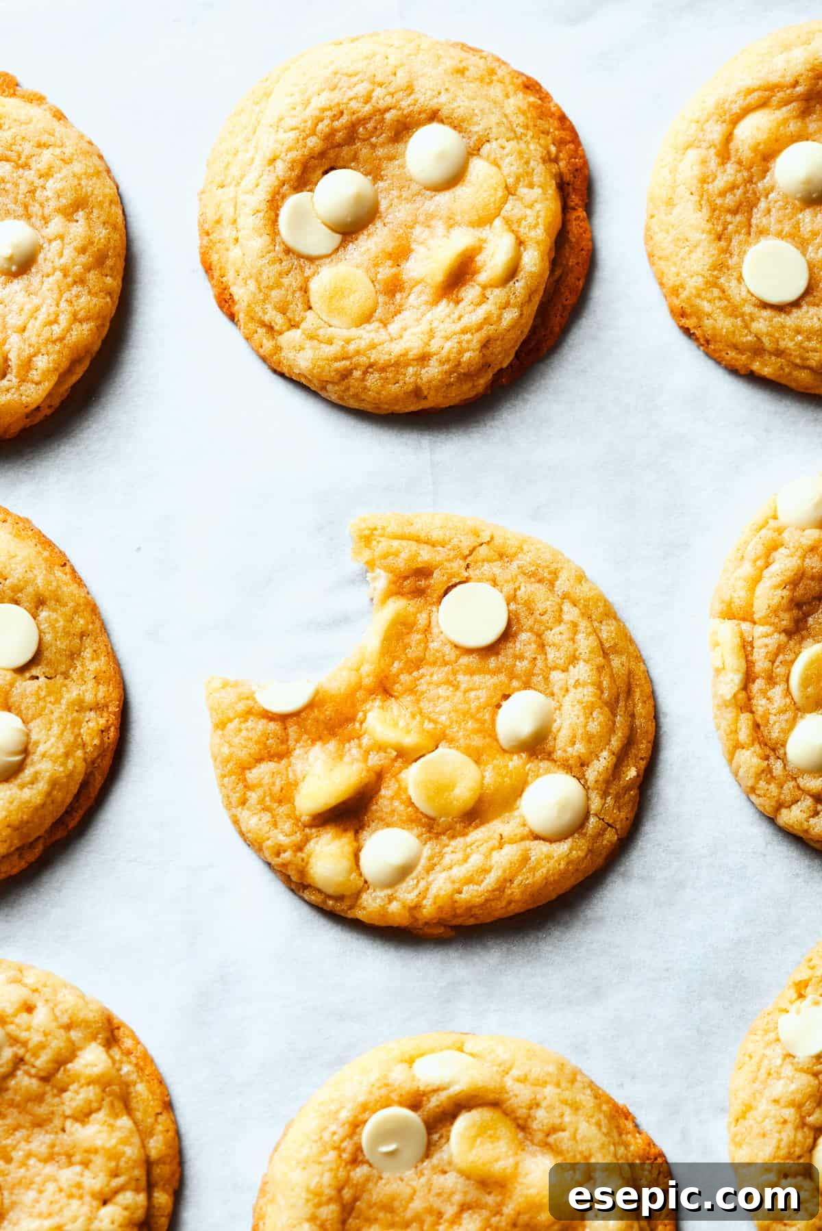 These chewy, buttery White Chocolate Chip Cookies are irresistibly packed with creamy, sweet white chocolate chips for an unexpected twist. Three golden brown white chocolate chip cookies are neatly stacked on a white plate, with the top cookie having a bite taken out of it, revealing its soft, chewy interior.
