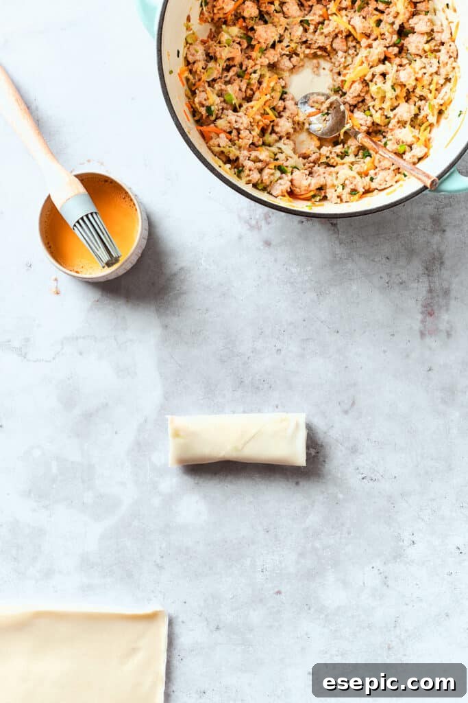 Egg wash is brushed on a chicken egg roll.