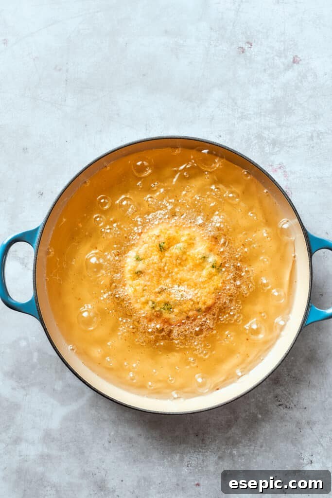 A shrimp patty sizzles and fries in hot oil, developing a beautiful golden-brown and crispy crust.