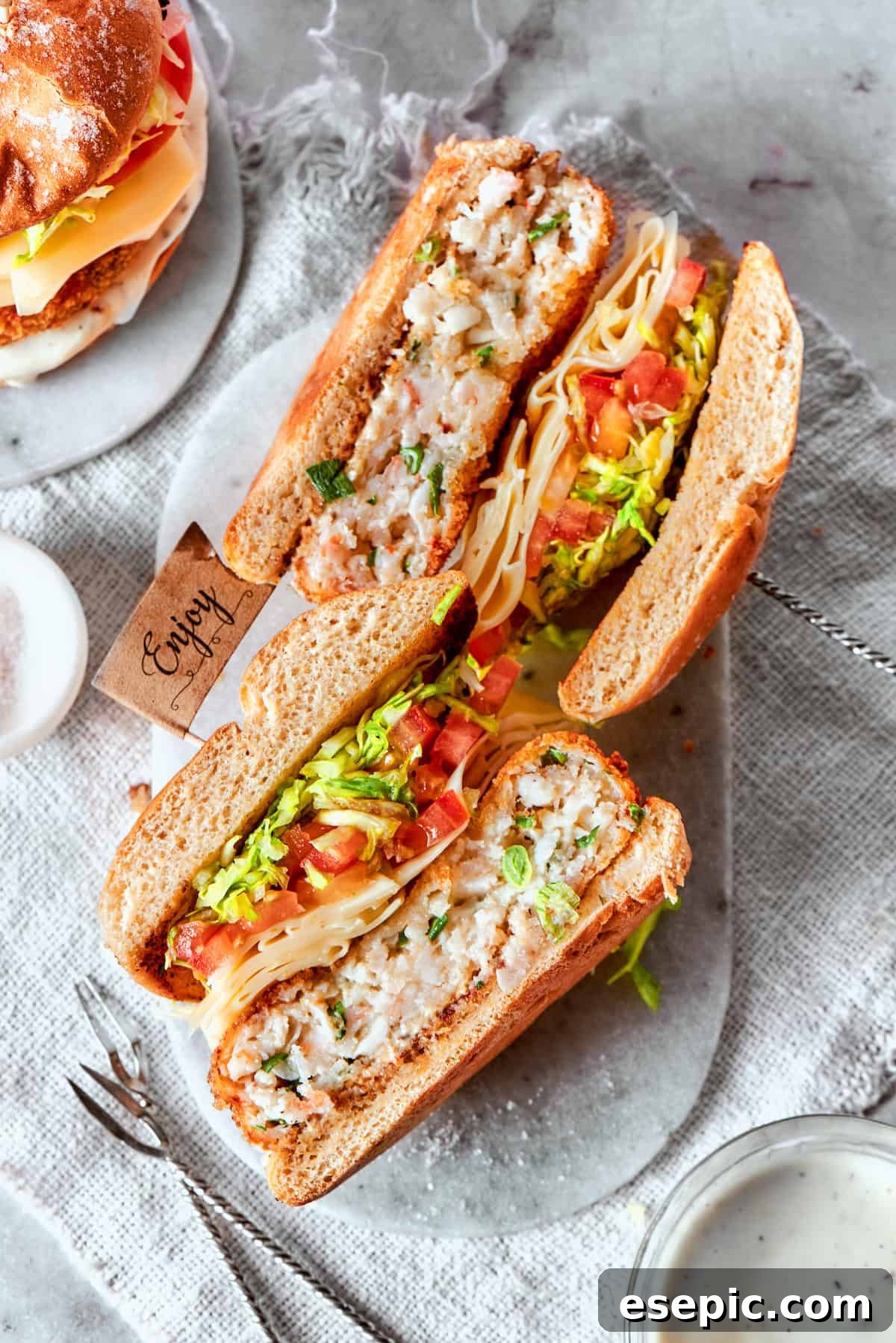 Two halves of a shrimp burger are arranged on their sides, showcasing the delicious layers of patty, cheese, and vegetables within.