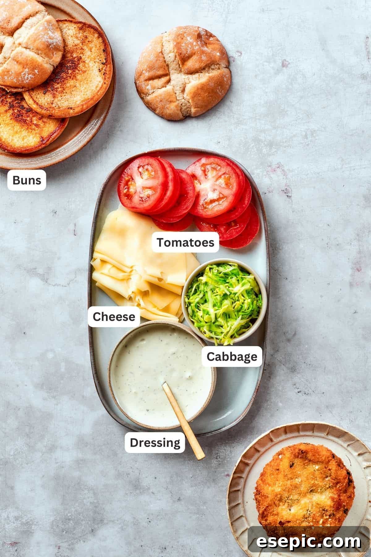 Ingredients for assembling shrimp burgers, including buns, tomatoes, cabbage, and dressing, are ready for final preparation.