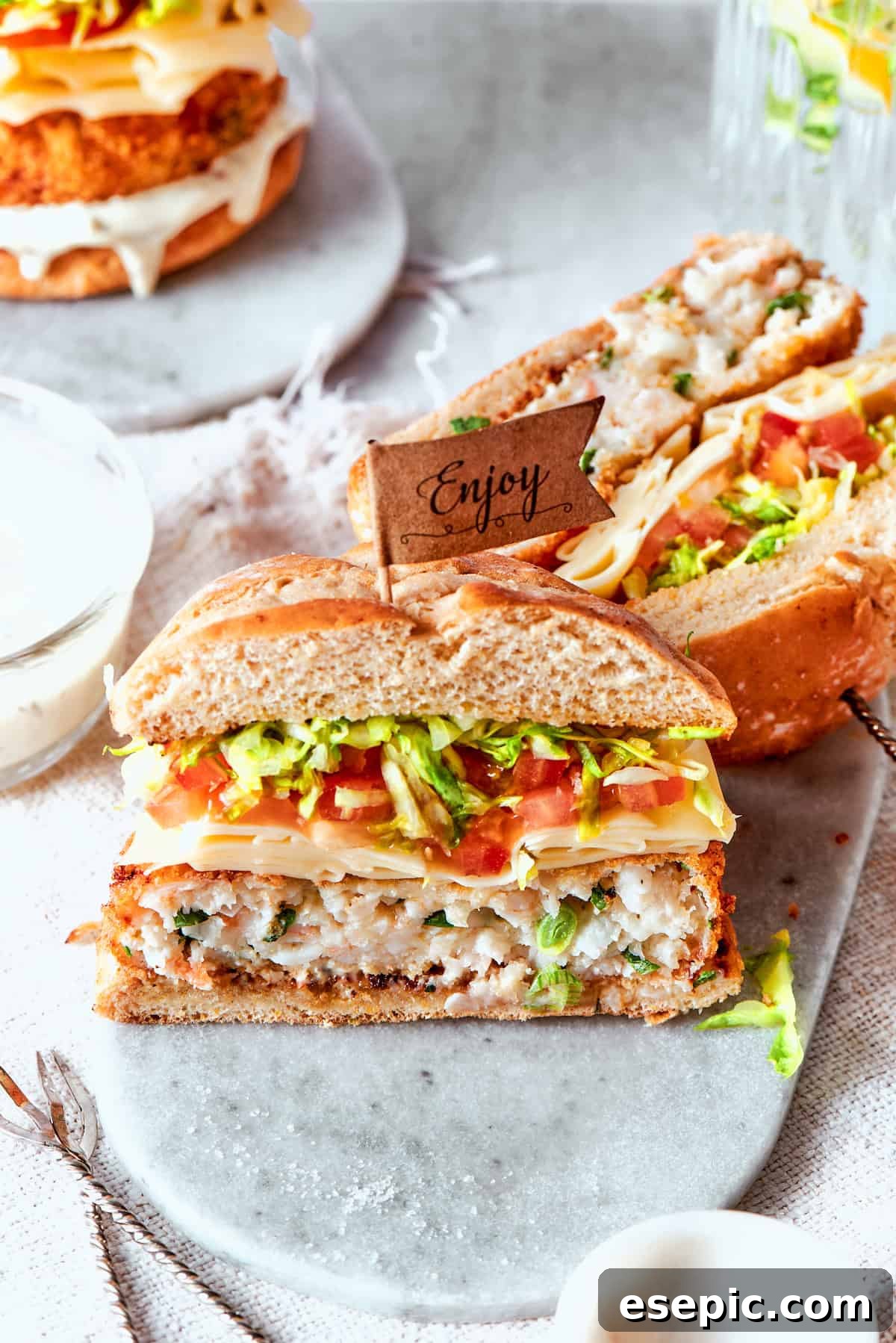 Two shrimp burgers are neatly cut in half, revealing their perfectly cooked, tender interiors and crispy golden crusts.
