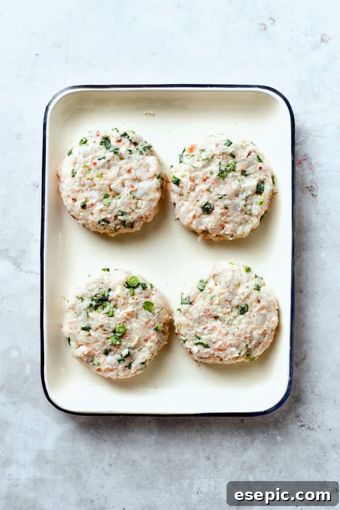 Four perfectly formed shrimp patties are arranged on a tray, ready for the next step in the cooking process.