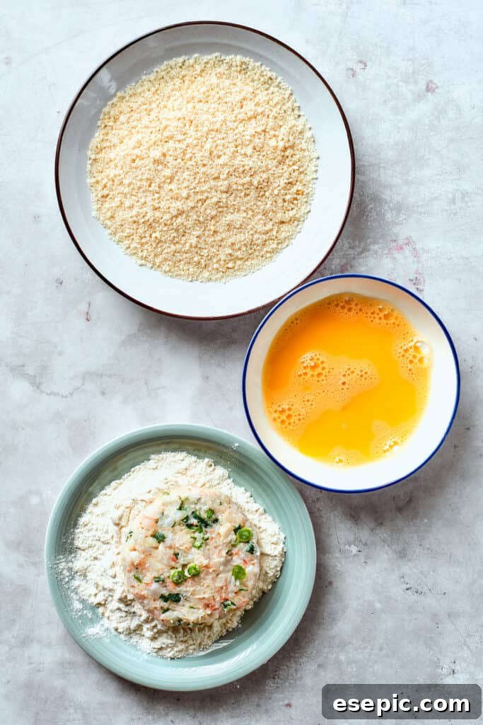 A shrimp patty is carefully dipped into flour, forming the first layer of its crispy breading.