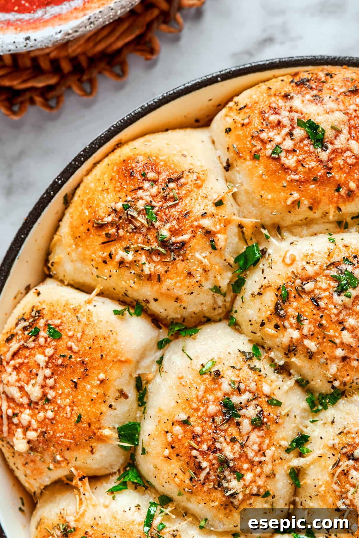 Half of the skillet of baked pizza bites topped with herbs.