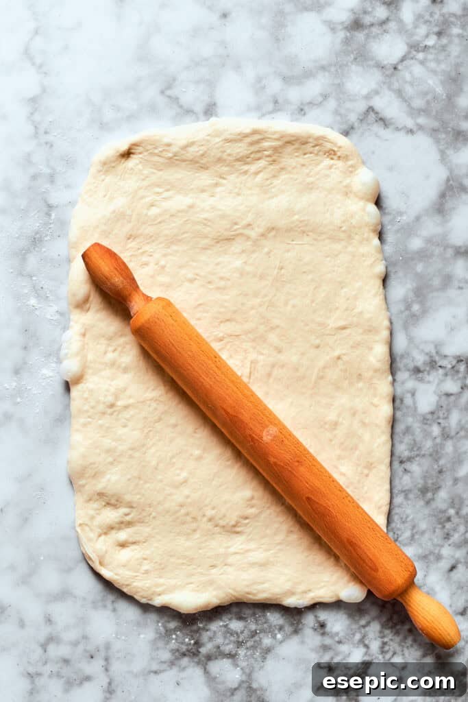 The pizza dough is rolled out with a rolling pin.