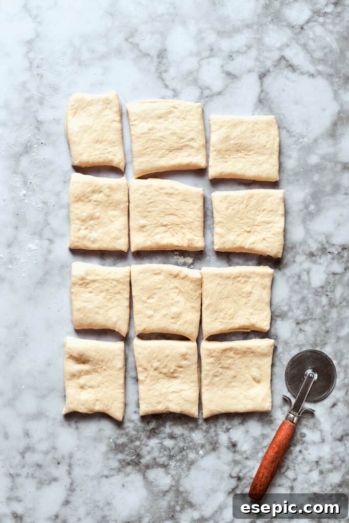 The pizza dough is cut into 12 squares.