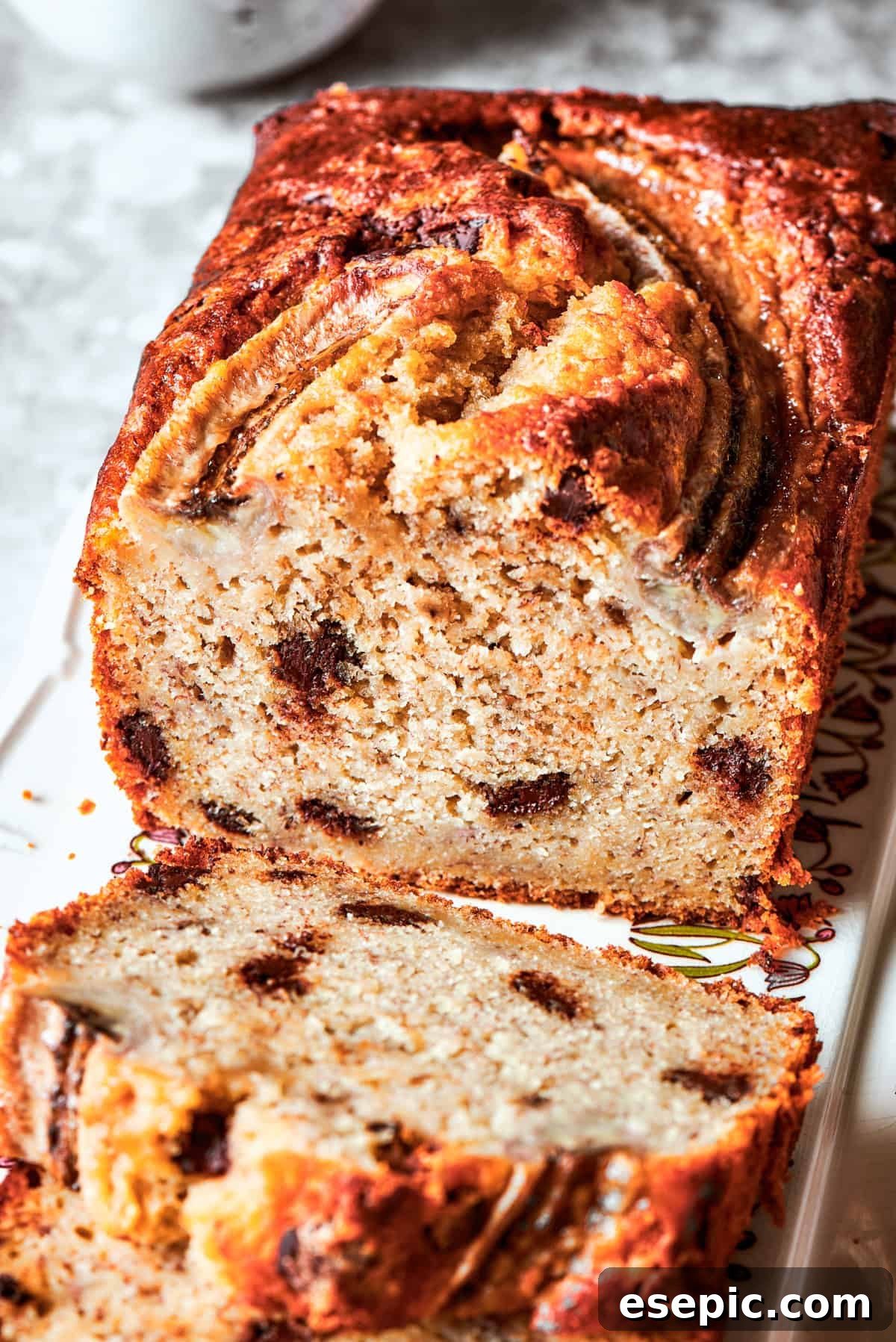 A close-up view of a slice of sour cream banana bread, showcasing its incredibly moist interior, visible chocolate chips, and tender crumb.