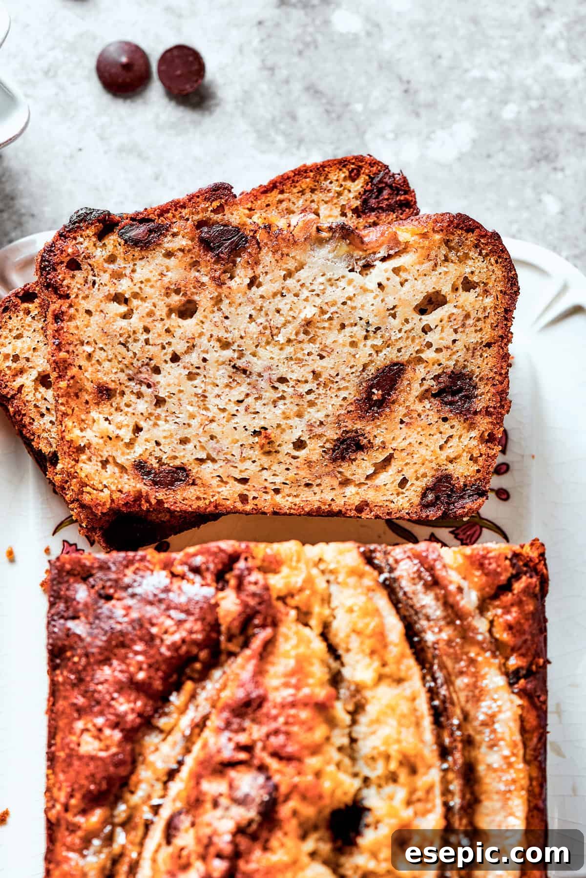 An overhead shot showcasing a baked sour cream banana bread loaf with two inviting slices cut out, revealing its moist texture and chocolate chips.