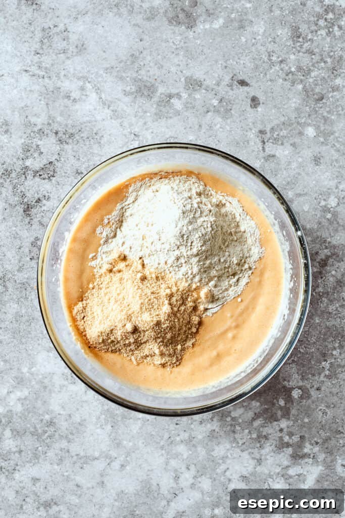 All-purpose flour and almond flour are added to the wet mixture, ready to be gently combined to form the rich banana bread batter.