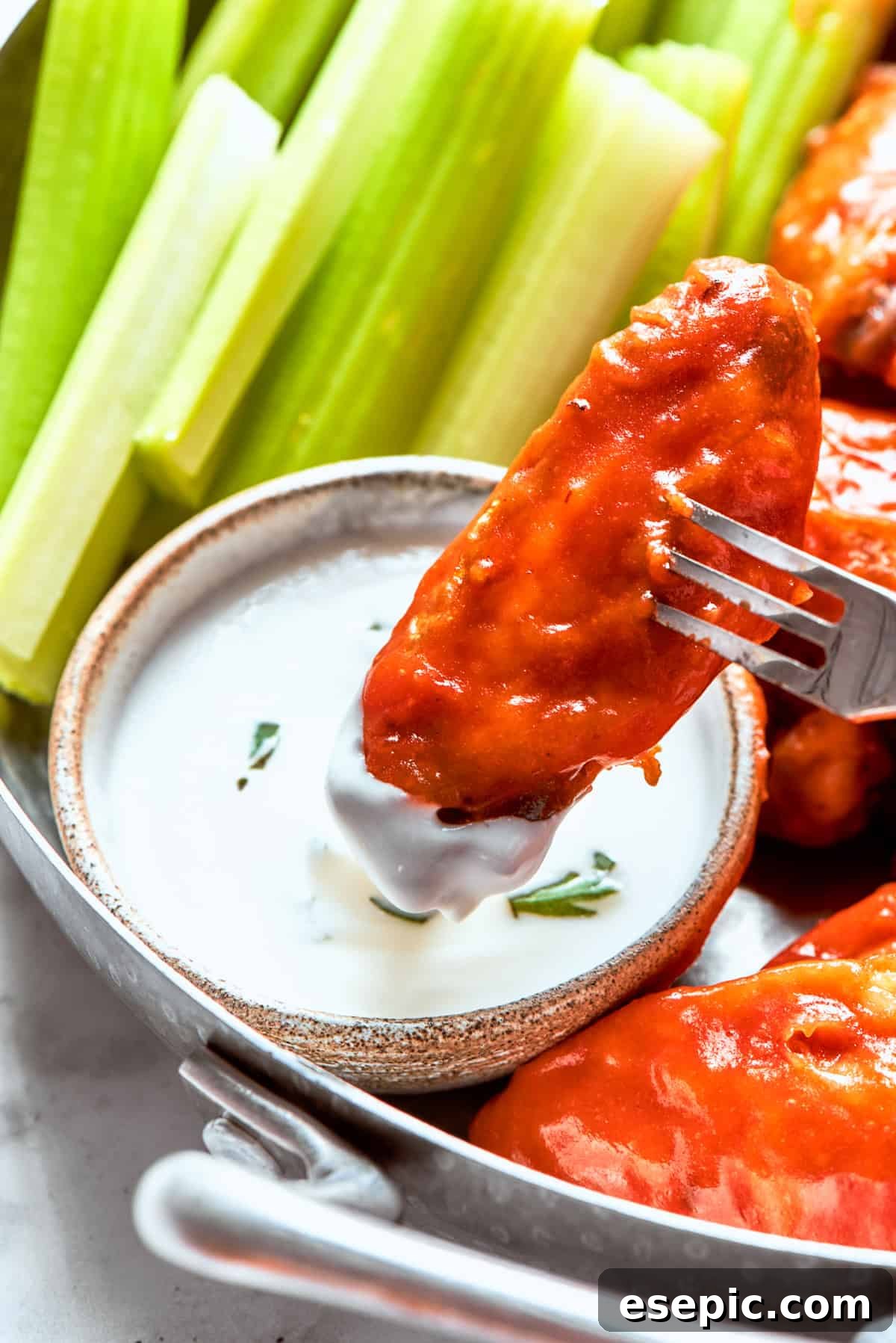 Dipping a chicken wing into ranch sauce.