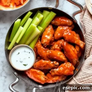 A view of a table holding a towel and a pan with buffalo wings, sauce, and celery.