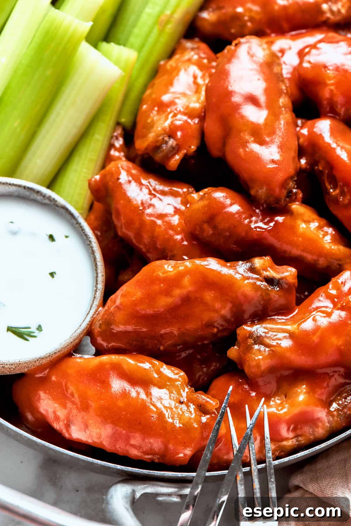 Buffalo wings in a dish with dipping sauce and celery.