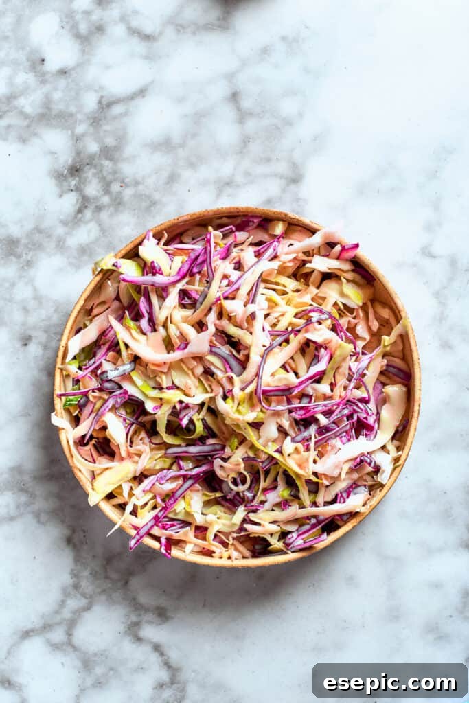The vibrant dressing is poured over the crunchy coleslaw mix, ready to be tossed and combined.