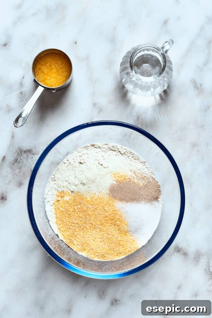 The dry ingredients for deep dish pizza crust: flour, cornmeal, instant yeast, sugar, and salt, artfully arranged in a bowl.
