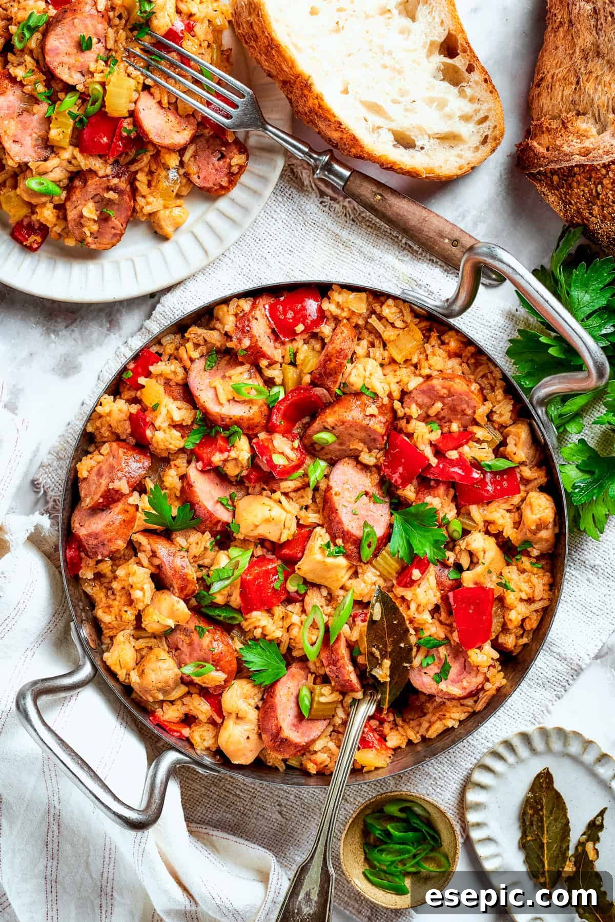 A big pan of chicken and sausage jambalaya on a table with bread.