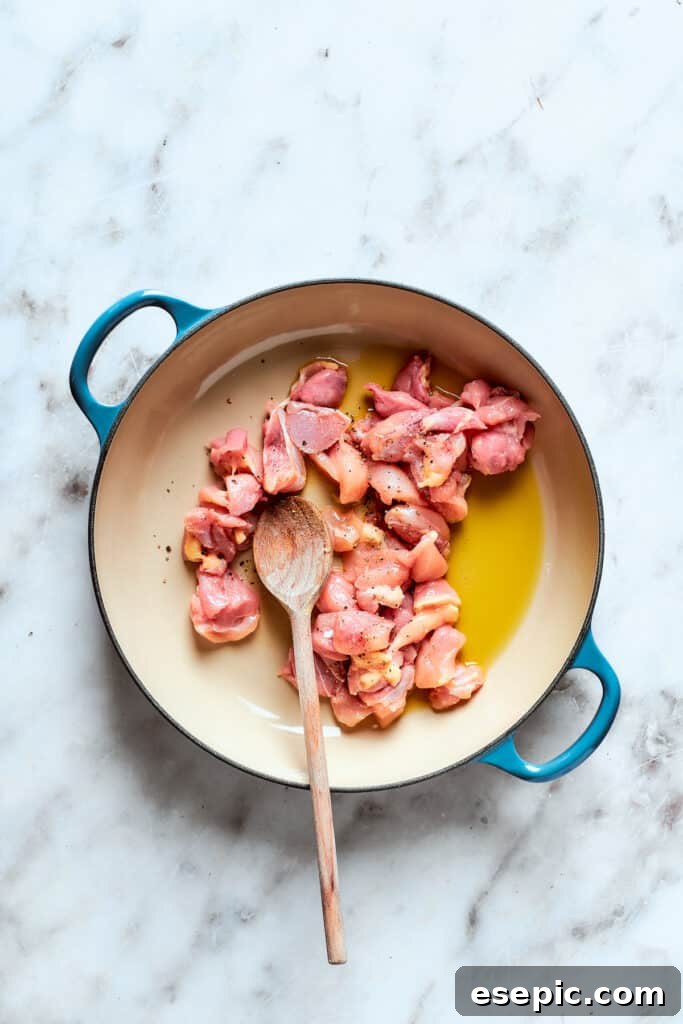 Chicken cooks in olive oil in a pot.