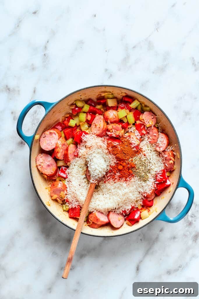 Spices and rice are added to the pot of jambalaya.