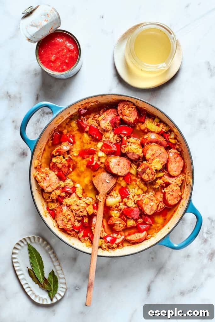 A wooden spoon stirs the jambalaya together.
