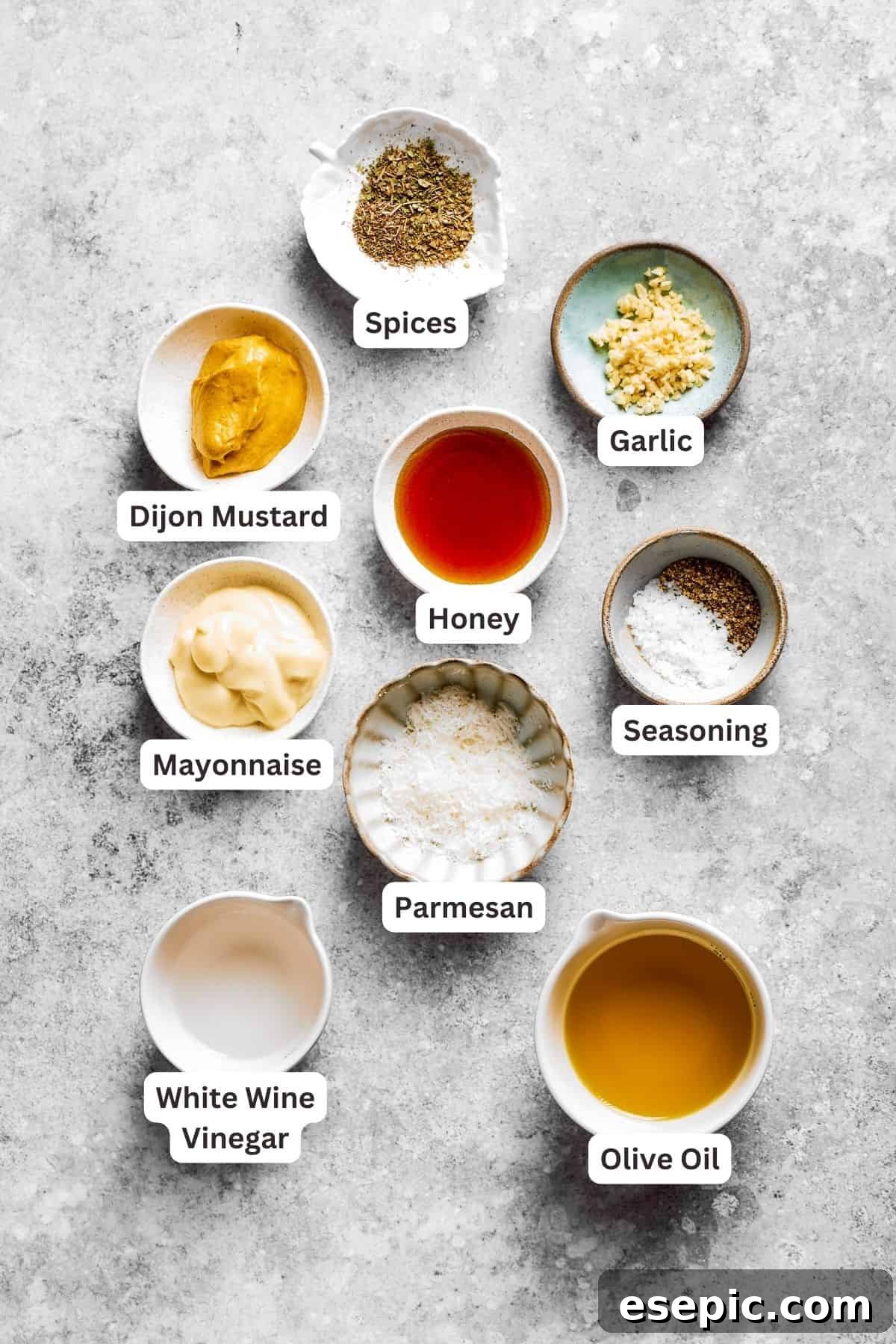 Labeled ingredients for the homemade Italian dressing for spaghetti salad, including Dijon mustard, white wine vinegar, honey, dried herbs, Parmesan, mayonnaise, garlic, and seasoning salt.