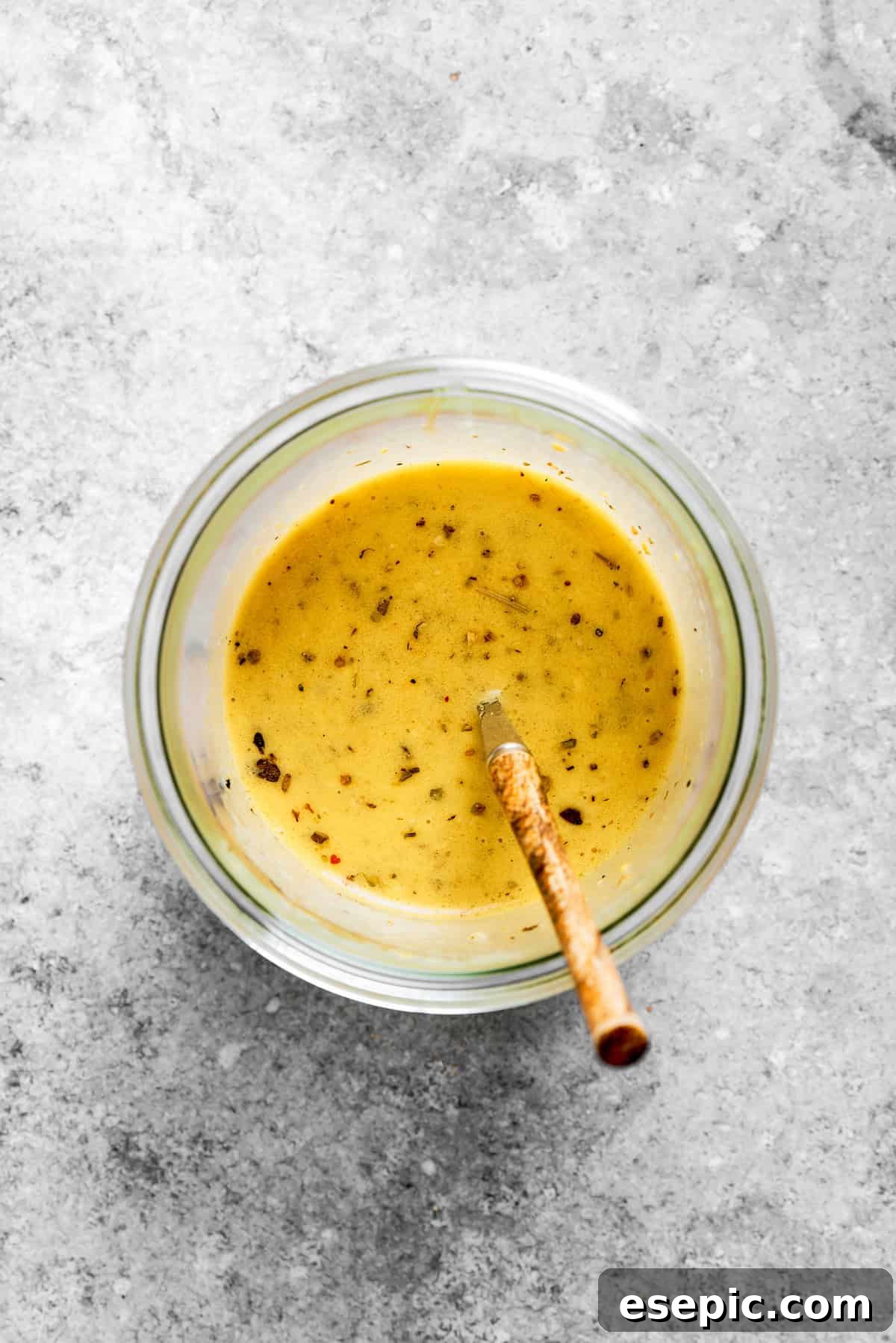 The homemade Italian dressing being whisked together in a small bowl, showcasing its creamy and well-emulsified texture.