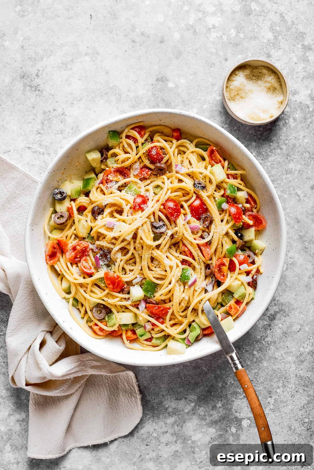 A large bowl of spaghetti salad showing all the colorful vegetables mixed in with the noodles and dressing, ready to be served.