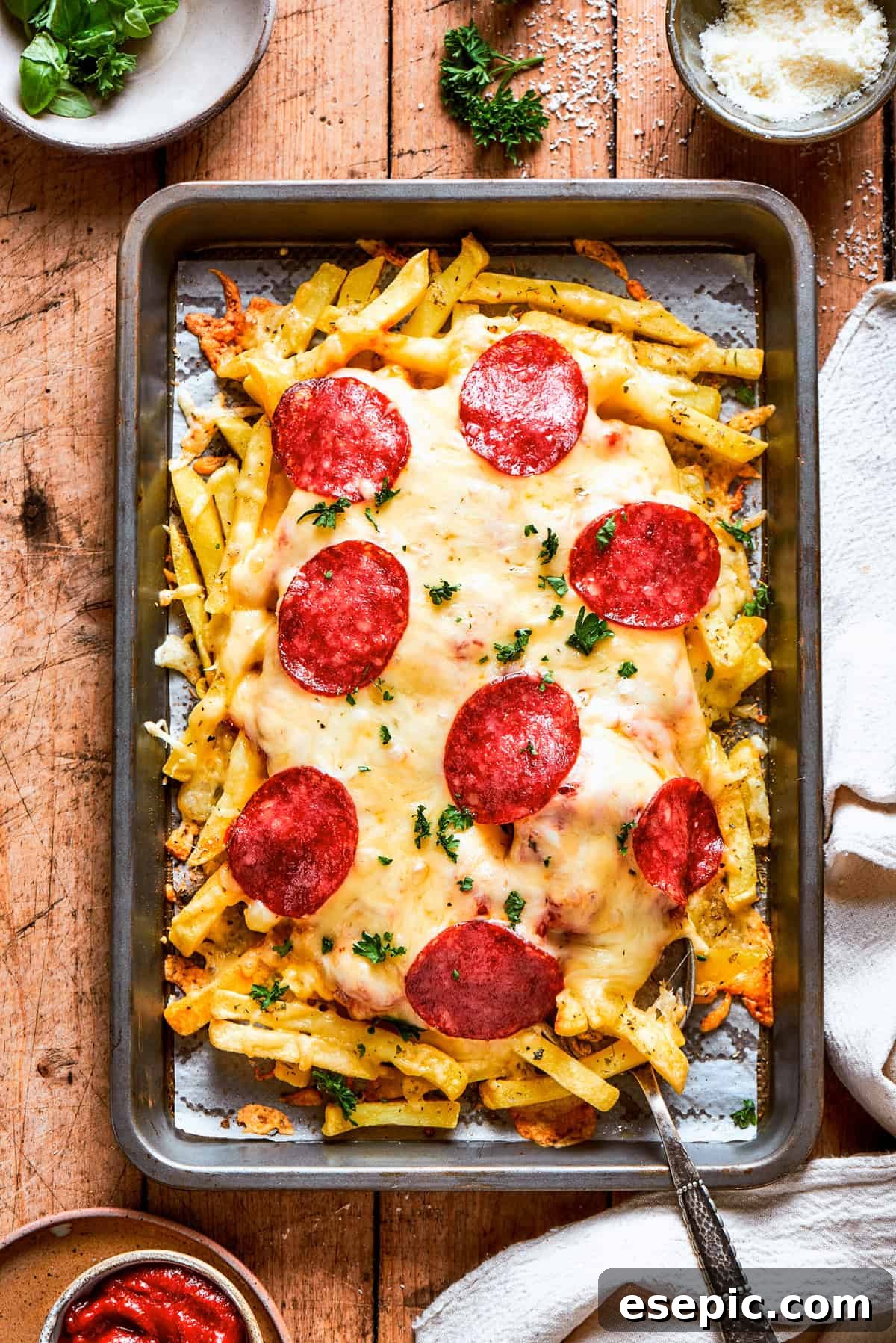 Pizza Fry Fusion 9 A baking tray with french fries topped with melted cheese and pepperoni.