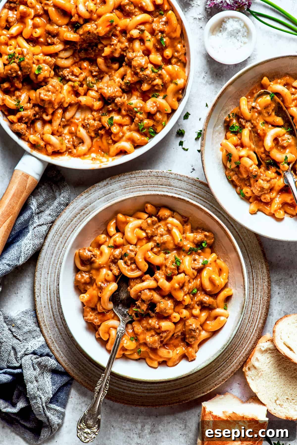 Two bowls of homemade Hamburger Helper, with a spoon stirring through one bowl, showing the rich and creamy beef and macaroni dish.