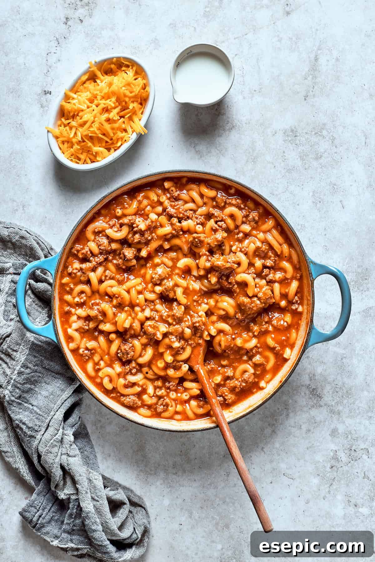 A spoon stirring together the perfectly cooked pasta and beef in a rich sauce, ensuring even distribution.