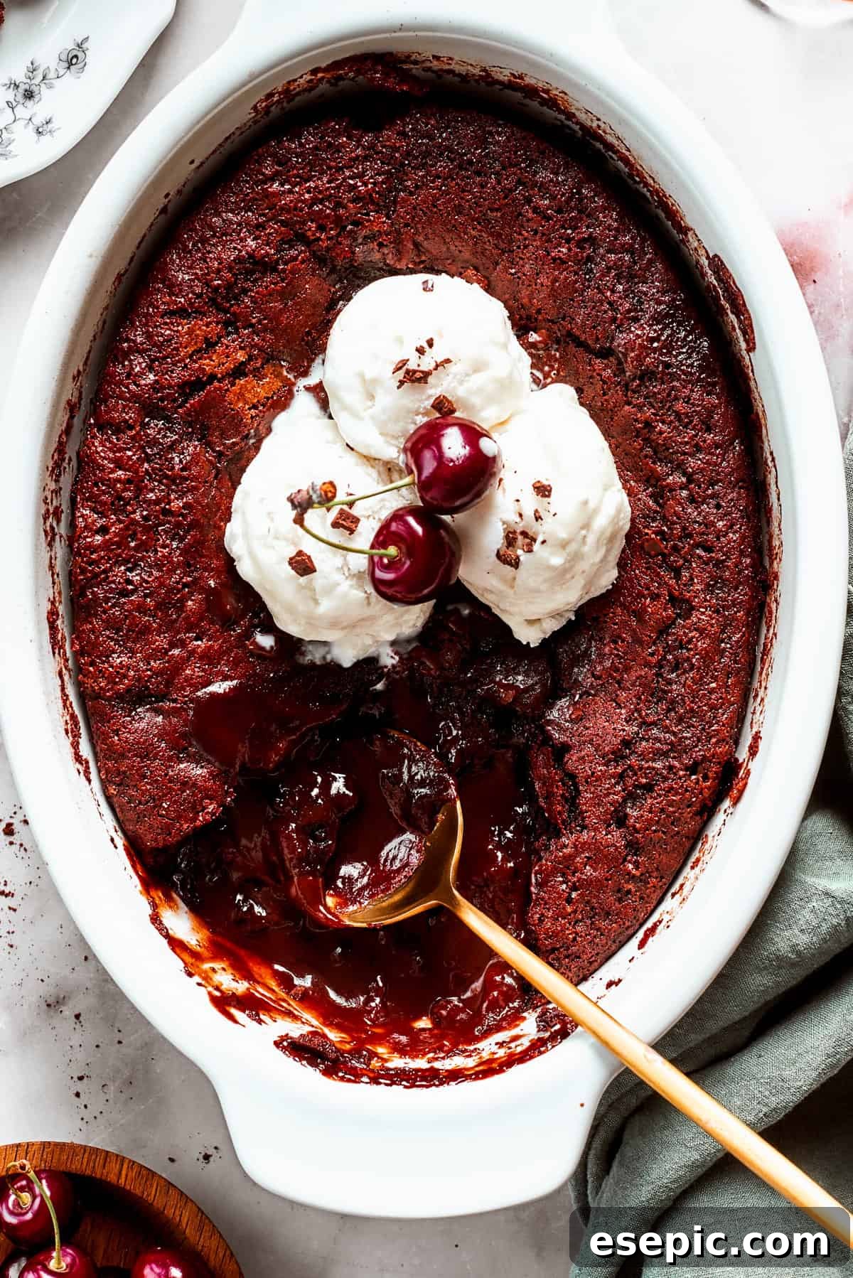 This moist and gooey Chocolate Pudding Cake is loaded with rich chocolate flavor in every bite. Best served warm! An oval casserole dish with chocolate pudding cake topped with vanilla ice cream, with a spoon set in the pudding.