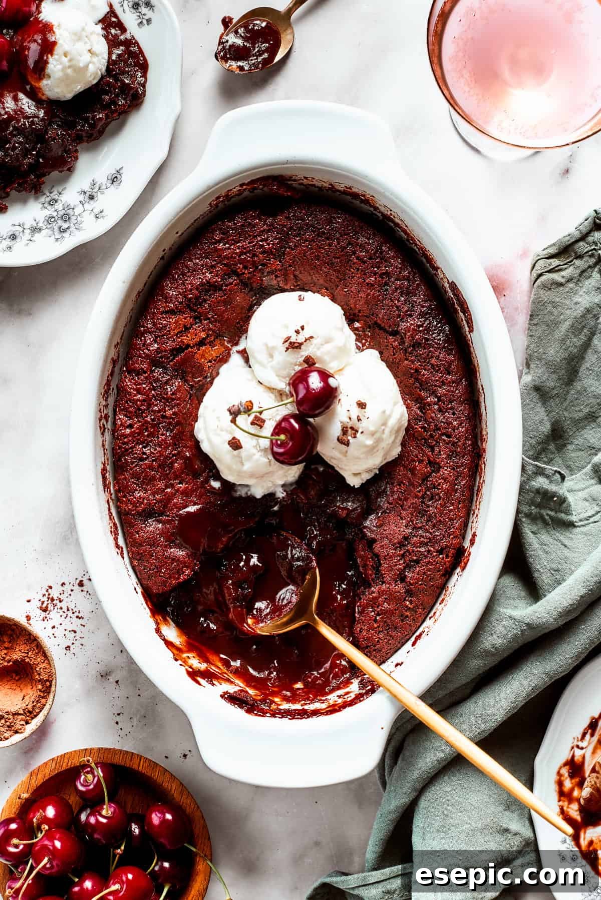 This moist and gooey Chocolate Pudding Cake is loaded with rich chocolate flavor in every bite. Best served warm! Chocolate cake in a casserole dish garnished with vanilla ice cream scoops, two cherries, with a gold-colored spoon set inside the cake.